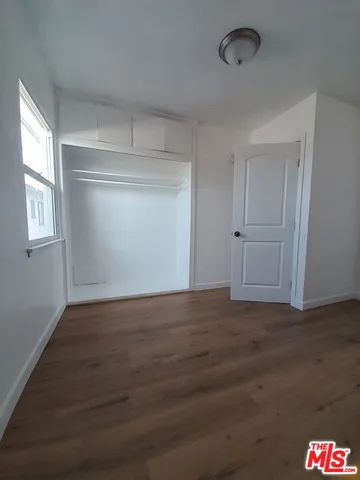a view of an empty room with wooden floor and window