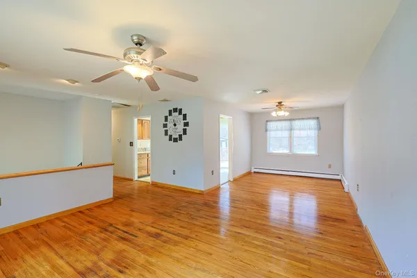a view of an empty room with window and wooden floor