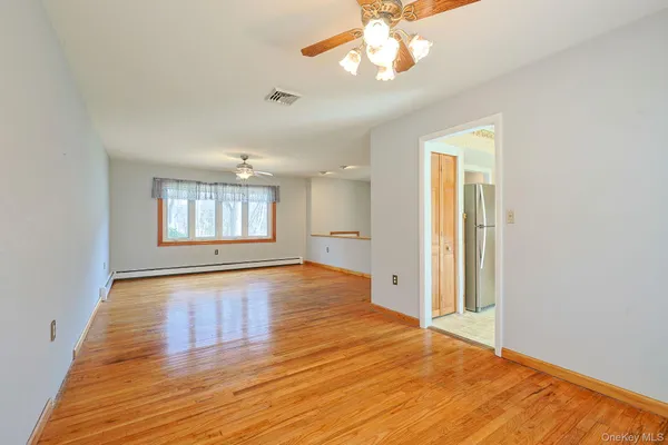 a view of an empty room with a window and wooden floor