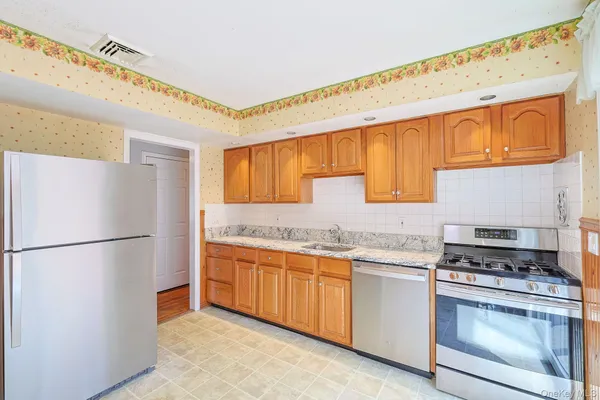 a kitchen with stainless steel appliances granite countertop a refrigerator a stove and a sink