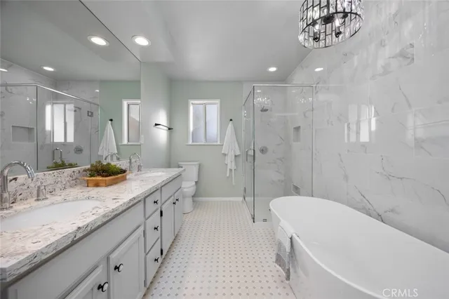 a spacious bathroom with a granite countertop sink a toilet a large mirror a bathtub and shower