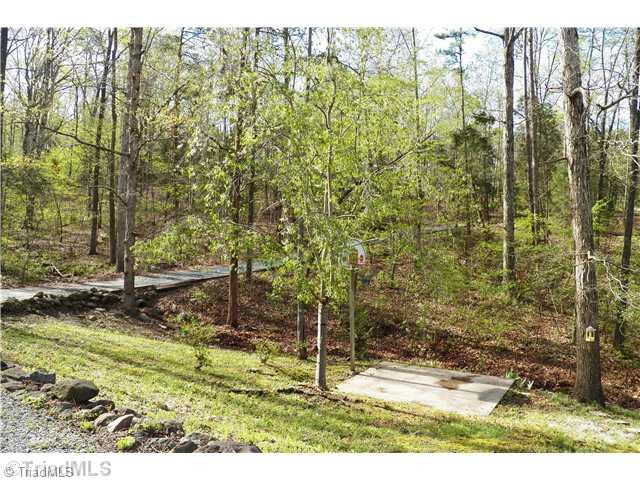 560 Lake Ridge Trail Denton, NC 27239 - Photo 14 of 16 Exterior Back. Beautiful natural setting. View of road side yard and woods with semi-private drive entrance. Small Basketball Court with pole and net.