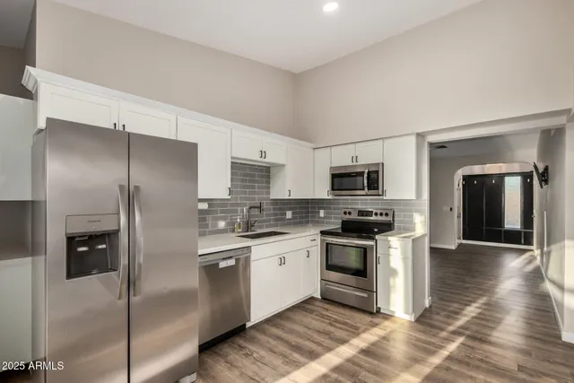 a kitchen with stainless steel appliances granite countertop a refrigerator a stove and a sink