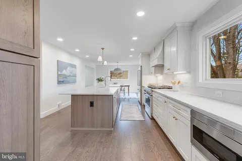 a large kitchen with a large counter top space a sink stainless steel appliances and cabinets