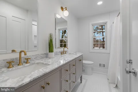 a bathroom with a granite countertop sink a toilet and mirror