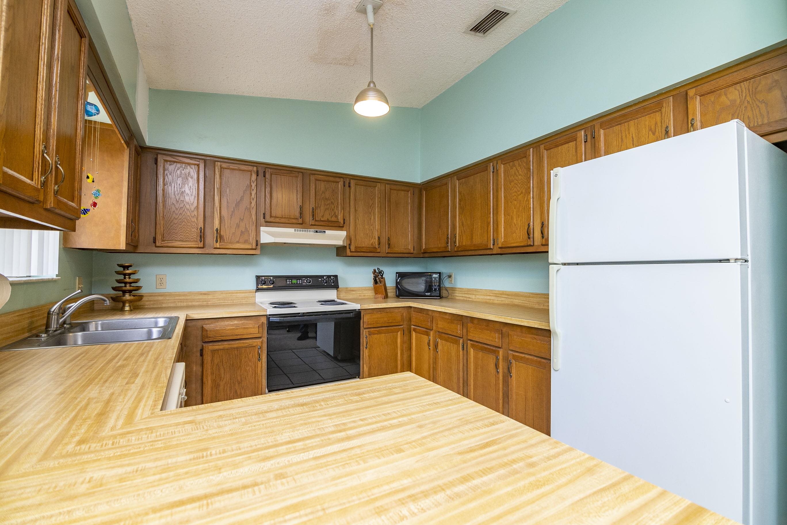 303 Cypress Road St. Augustine, FL 32086 - Photo 26 of 33 a kitchen with granite countertop wooden cabinets a stove a sink and a refrigerator