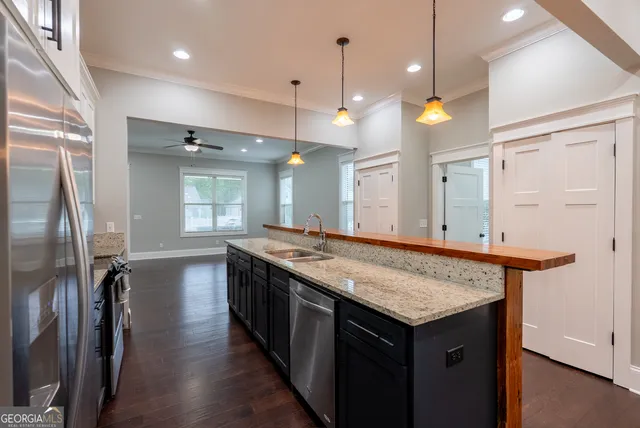 a kitchen with stainless steel appliances granite countertop a refrigerator a sink a stove and microwave with wooden floor