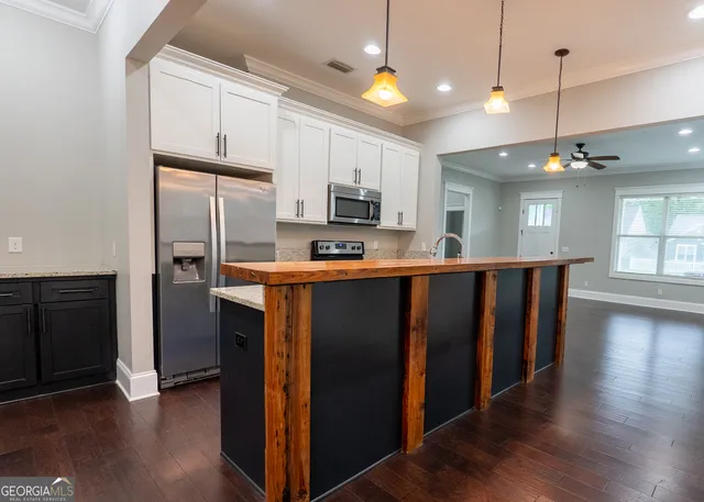 a kitchen with stainless steel appliances kitchen island granite countertop a refrigerator and a stove top oven