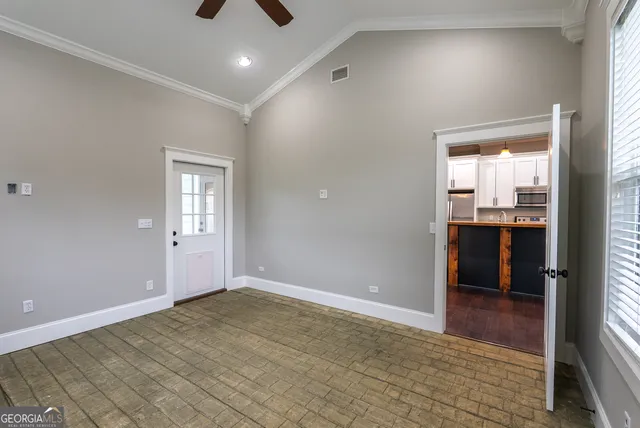 an empty room with wooden floor fan and windows