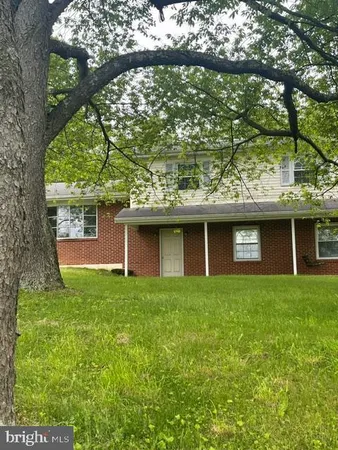 a brick house next to a yard with a large tree