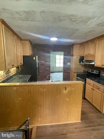 a living room with stainless steel appliances wooden floor dining table and kitchen view