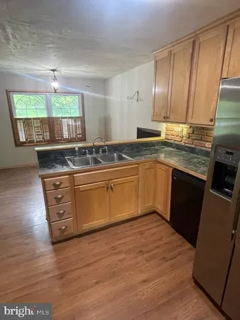 a kitchen with stainless steel appliances granite countertop wooden cabinets a stove top oven a sink and dishwasher with wooden floor