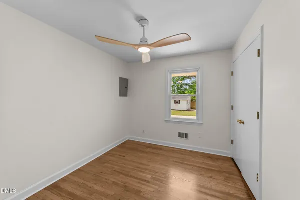 an empty room with window and ceiling fan