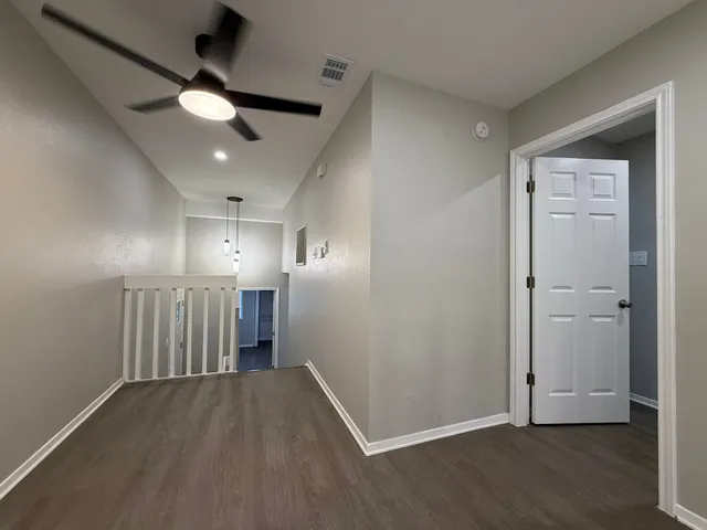 an empty room with wooden floor and a ceiling fan