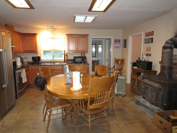 a dining area with stainless steel appliances kitchen island granite countertop a table chairs and a refrigerator