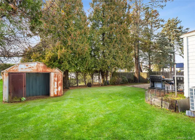 a view of a backyard with table and chairs and a large tree