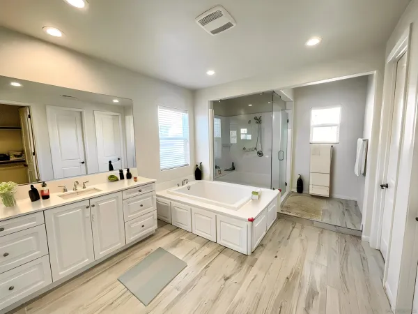 a large bathroom with a double vanity sink a large mirror and a bathtub