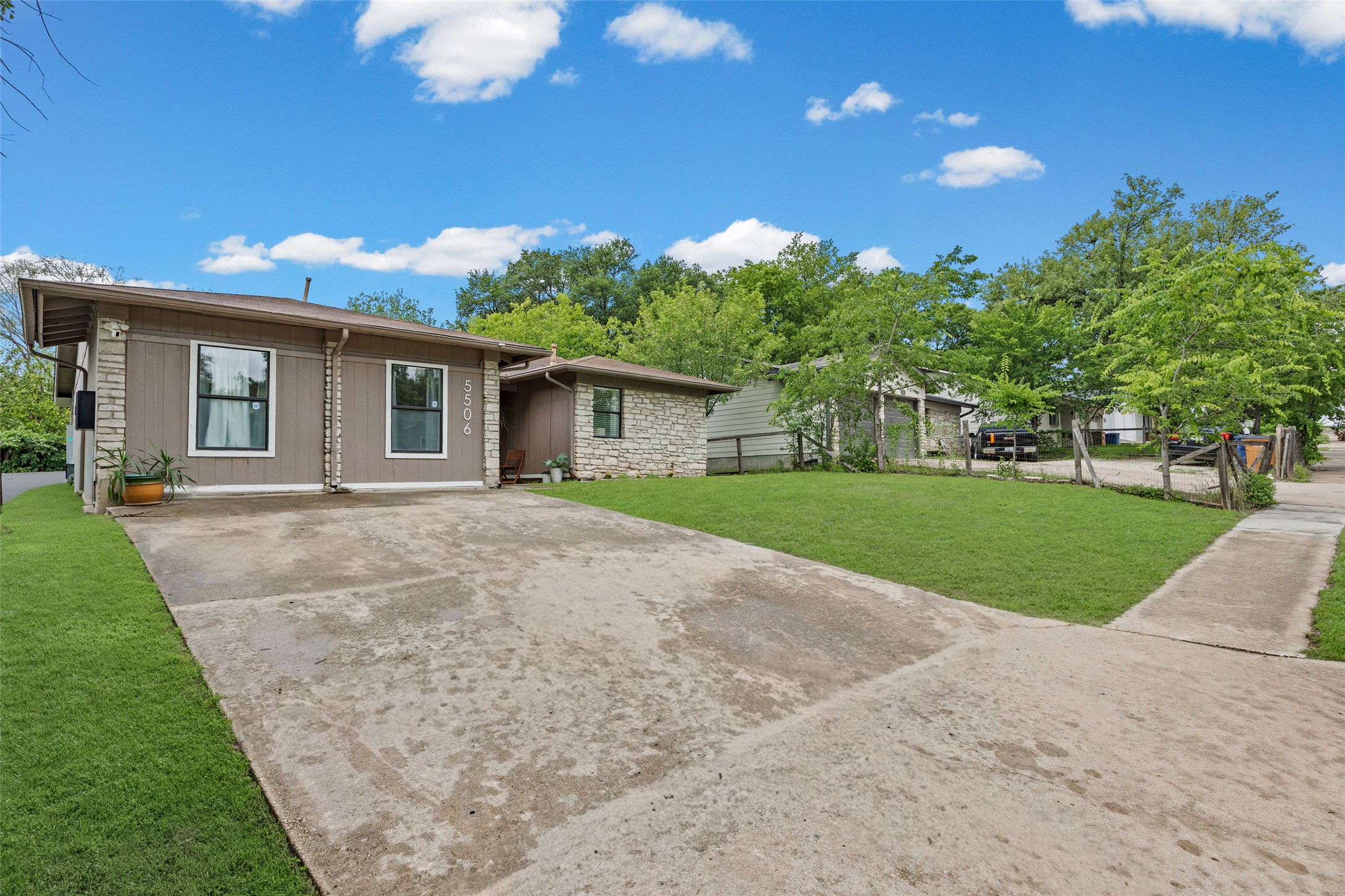 5506 South Pleasant Valley Road Austin, TX 78744 - Photo 24 of 25 A welcoming concrete driveway leads to a modest home with stone accents and mature surrounding trees.