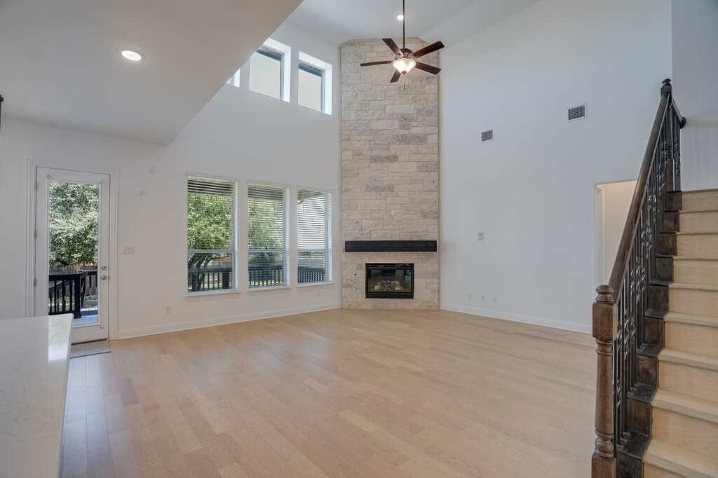 2920 Hadley Way Leander, TX 78641 - Photo 3 of 20 A tall stone fireplace anchors this living space, featuring high ceilings and light wood floors.