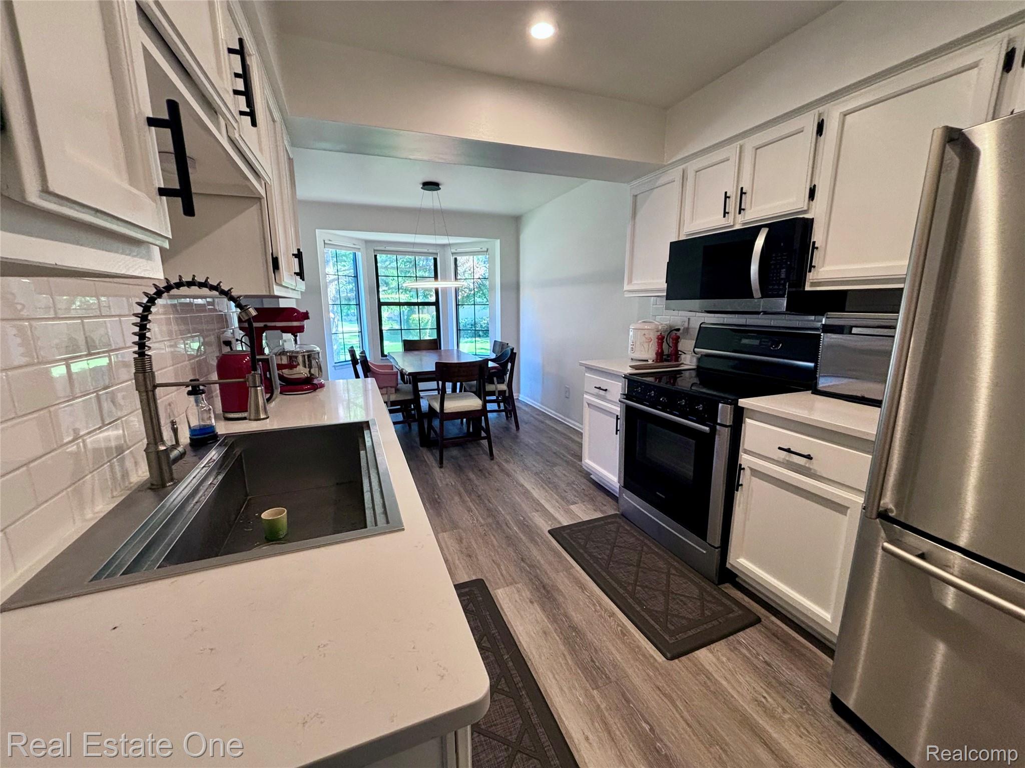 66 Meadow Wood Drive Rochester, MI 48307 - Photo 7 of 20 Kitchen featuring white cabinetry with matte black hardware, subway tile backsplash, and light-toned countertops