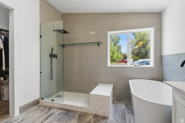 4270 River Road Oakley, UT 84055 - Photo 12 of 46 Modern bathroom featuring a freestanding soaking tub, a frameless glass shower enclosure with matte black fixtures, a built-in shower bench, and floor-to-ceiling tilework
