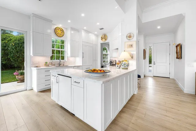 a large white kitchen with stainless steel appliances kitchen island granite countertop a large counter top and a stove