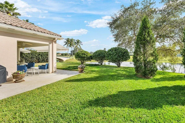 a view of a white house in front of a big yard with potted plants