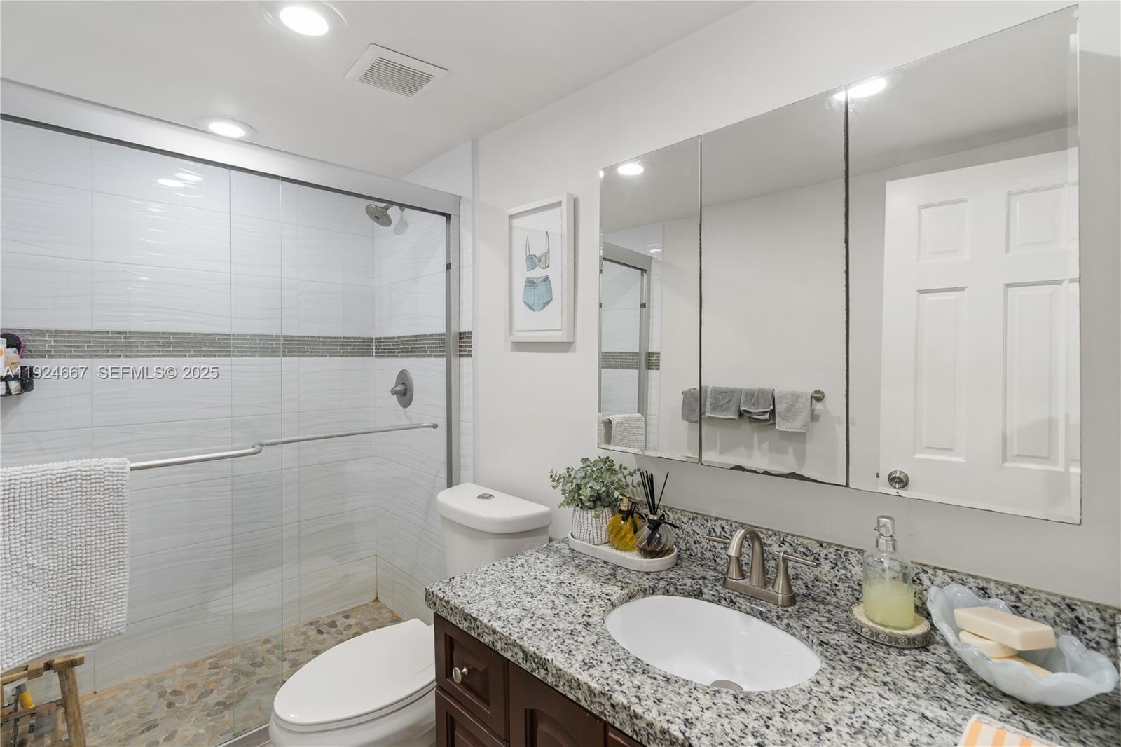 555 Crandon Boulevard, Unit 21 Key Biscayne, FL 33149 - Photo 16 of 32 a bathroom with a granite countertop sink a toilet a mirror and shower