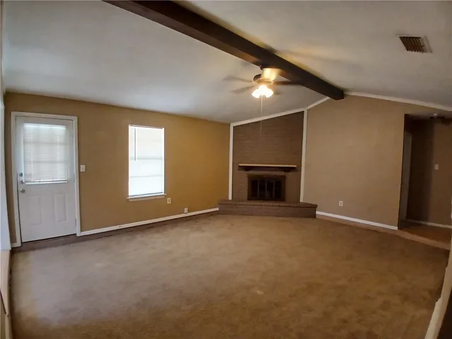 an empty room with windows and fireplace