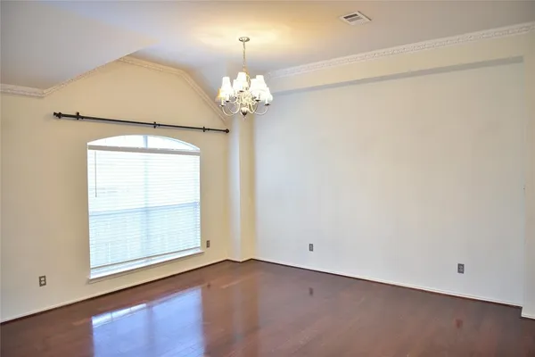 an empty room with wooden floor chandelier and window