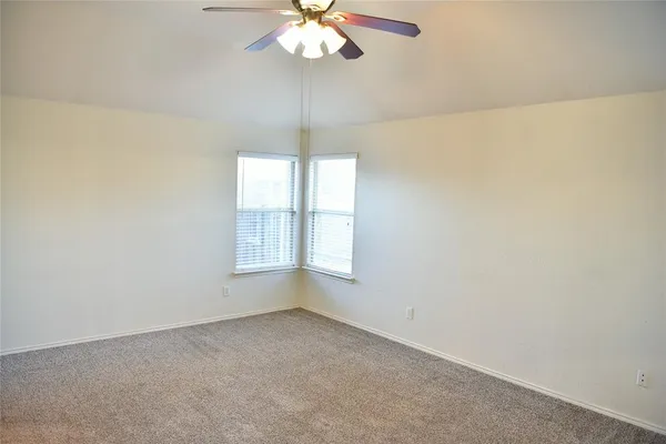 an empty room with a chandelier fan and windows