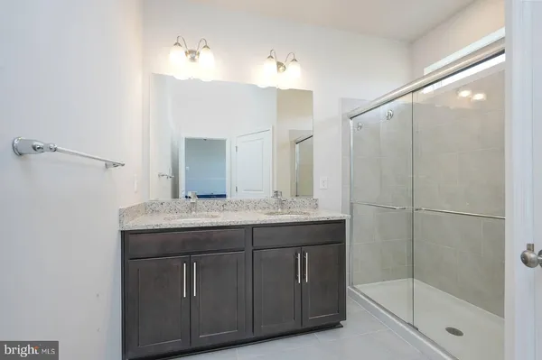 a bathroom with a granite countertop sink a mirror and a shower