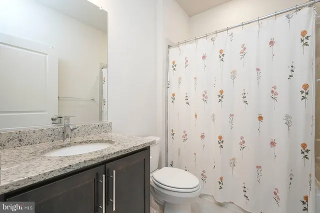a bathroom with a granite countertop sink toilet and a mirror
