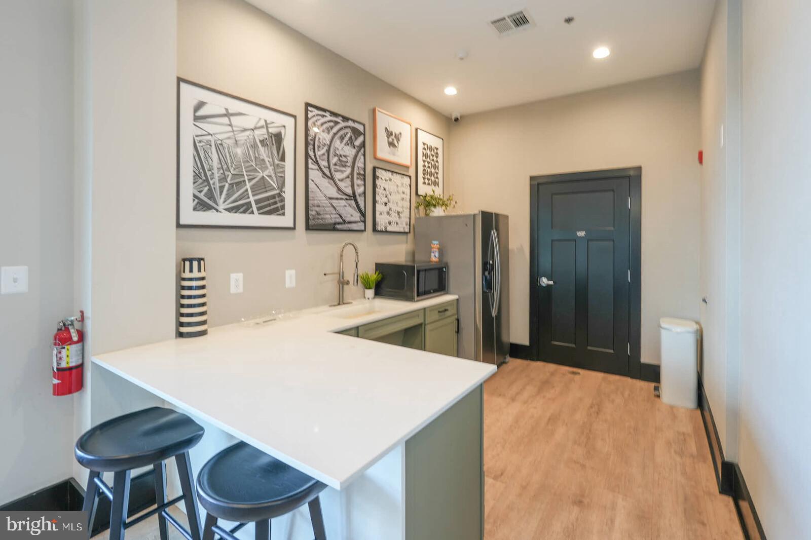 869 Amity Street Frederick, MD 21701 - Photo 46 of 48 a kitchen with stainless steel appliances kitchen island granite countertop a refrigerator a stove and a dining table with wooden floor