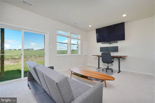 a living room with furniture a flat screen tv and a floor to ceiling window