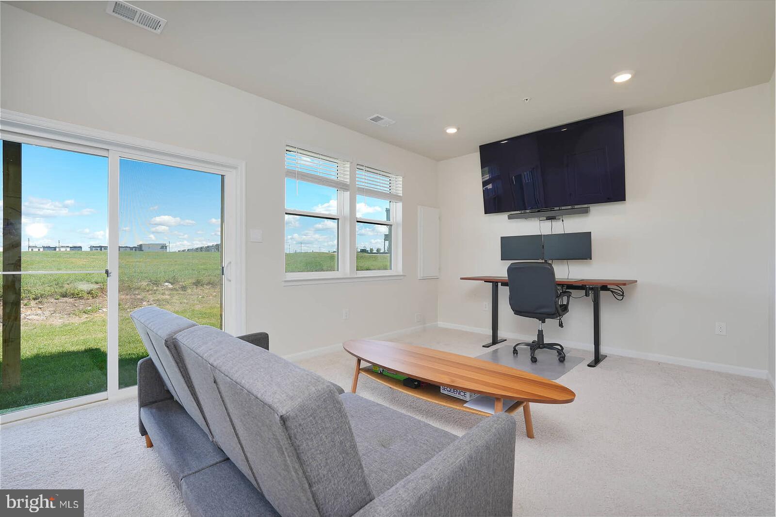 869 Amity Street Frederick, MD 21701 - Photo 5 of 48 a living room with furniture a flat screen tv and a floor to ceiling window