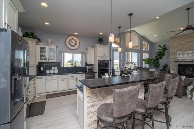 a large kitchen with granite countertop a large center island a sink stainless steel appliances and cabinets