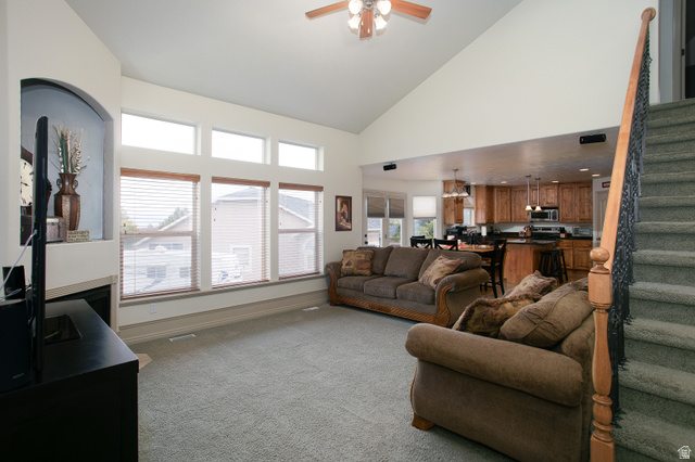 426 Deer Hollow Road Tooele, UT 84074 - Photo 5 of 37 Living area featuring stairway, light carpet, high vaulted ceiling, a fireplace, and a ceiling fan