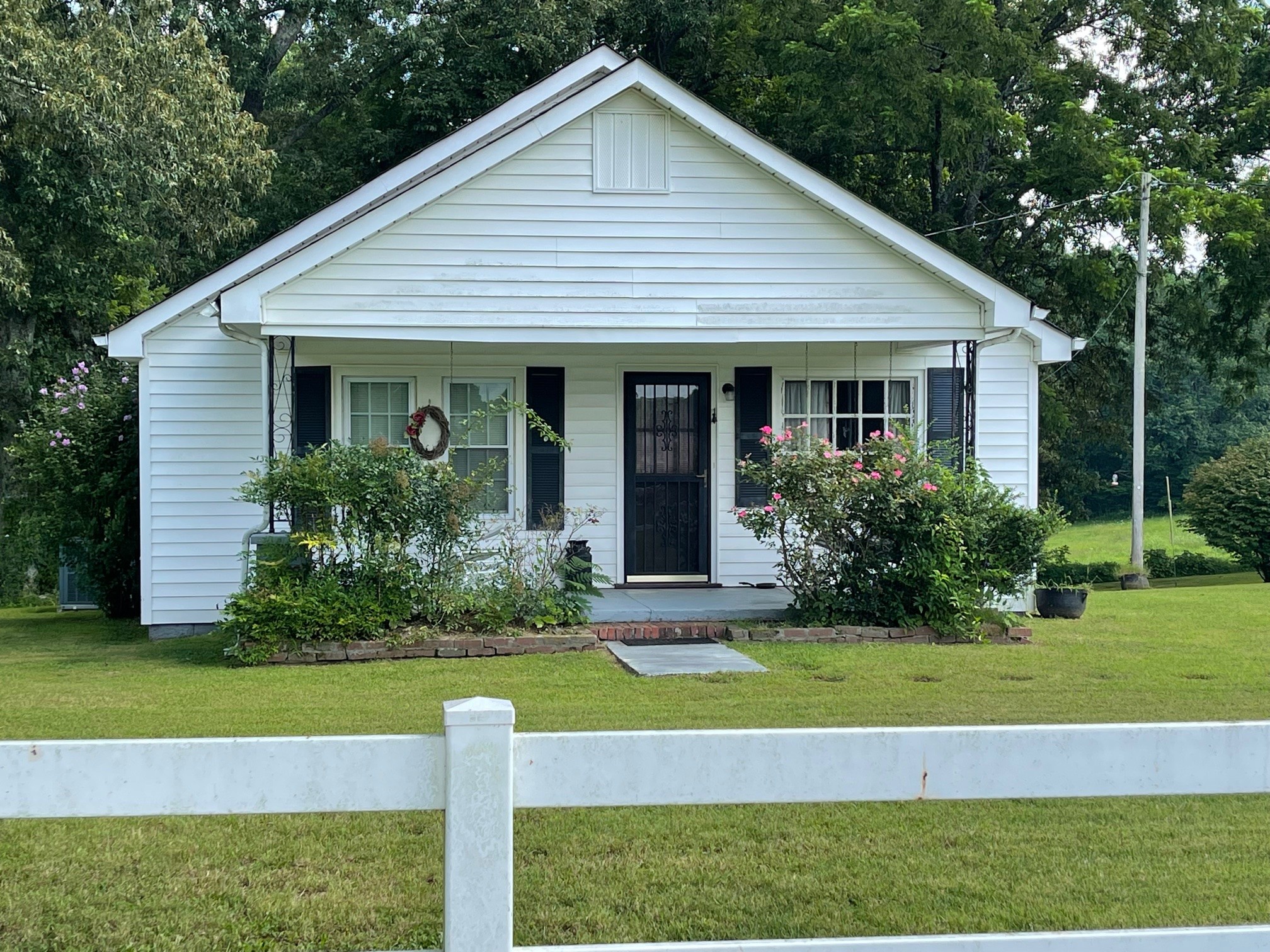7290 Chestnut Ridge Road Winchester, TN 37398 - Photo 2 of 13 a view of a white house next to a yard with plants and large trees