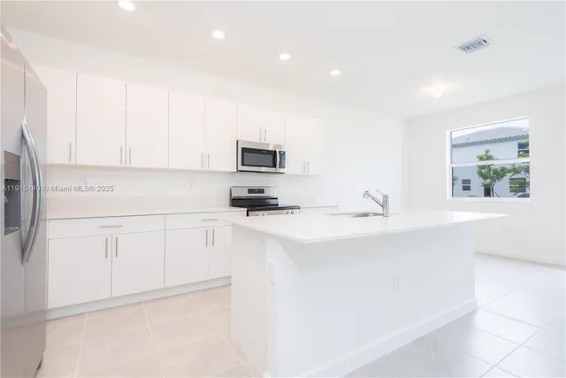 a kitchen with appliances a sink a window and a counter top space
