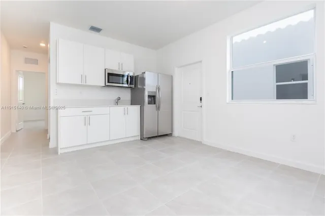 an empty room with kitchen view and a window