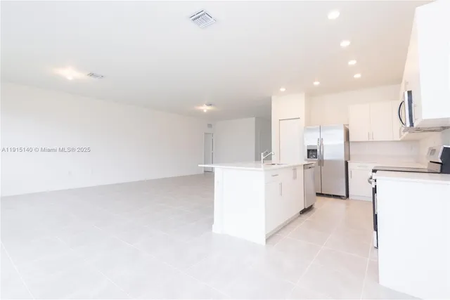 a view of kitchen with refrigerator and white cabinets
