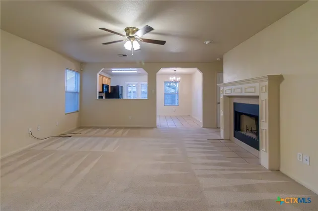 a view of a livingroom with a fireplace a ceiling fan and entryway