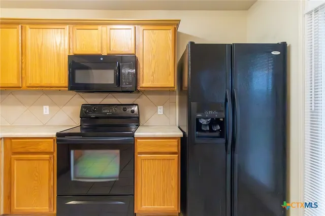 a kitchen with stainless steel appliances granite countertop a refrigerator and a stove top oven