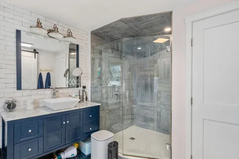 a bathroom with a sink vanity granite shower and a mirror