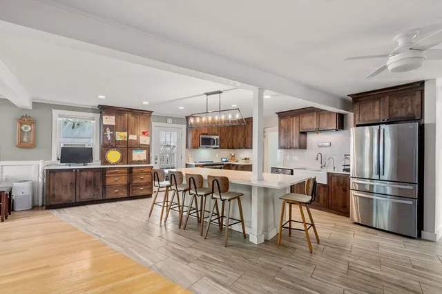 a kitchen with stainless steel appliances a refrigerator a stove a dining table and chairs with wooden floor