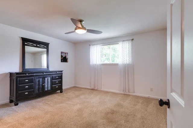 a view of an empty room with a dresser and a window