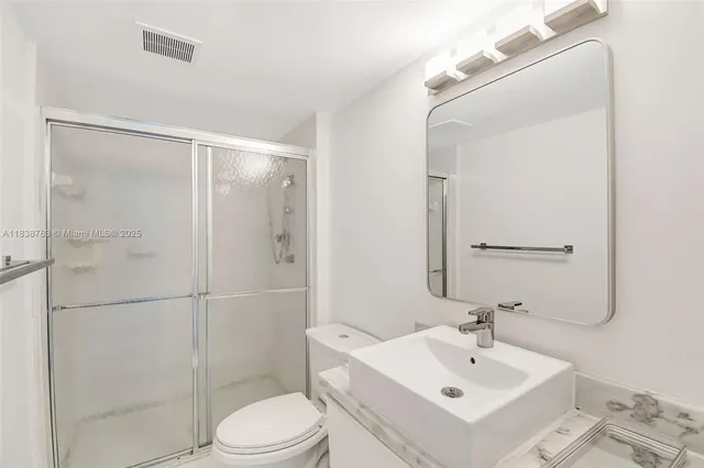 a bathroom with a sink mirror shower and toilet