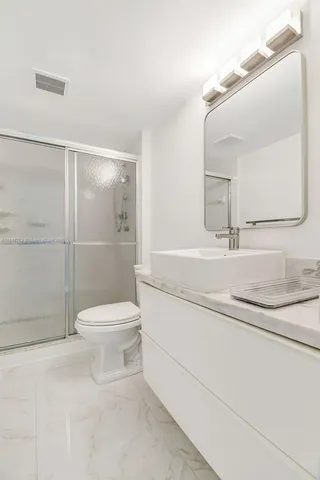 a bathroom with a granite countertop sink toilet a mirror and shower