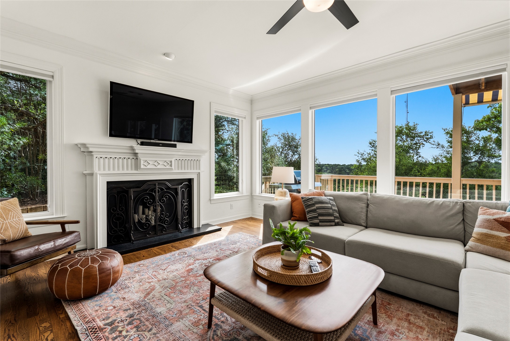 3107 Lookout Lane Austin, TX 78746 - Photo 11 of 39 A vibrant living area with rich hardwood floors, a classic fireplace, and expansive windows offering a beautiful natural view.